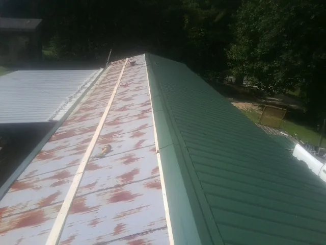Old rusted panels beside newly installed green metal roofing — Wind Damage Roof Repair by Roofing Brothers in New Baltimore