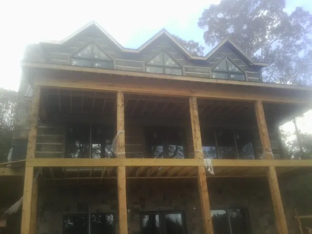Dormers and porch framing on a large log home under construction — Roof Coating work by our crew in New Baltimore