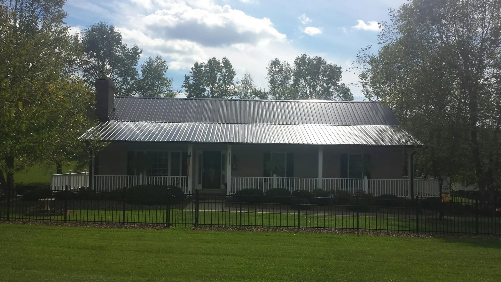 Gray metal roof on a brick ranch with a full width front porch — Gutter Guard Installation work by our crew in New Baltimore