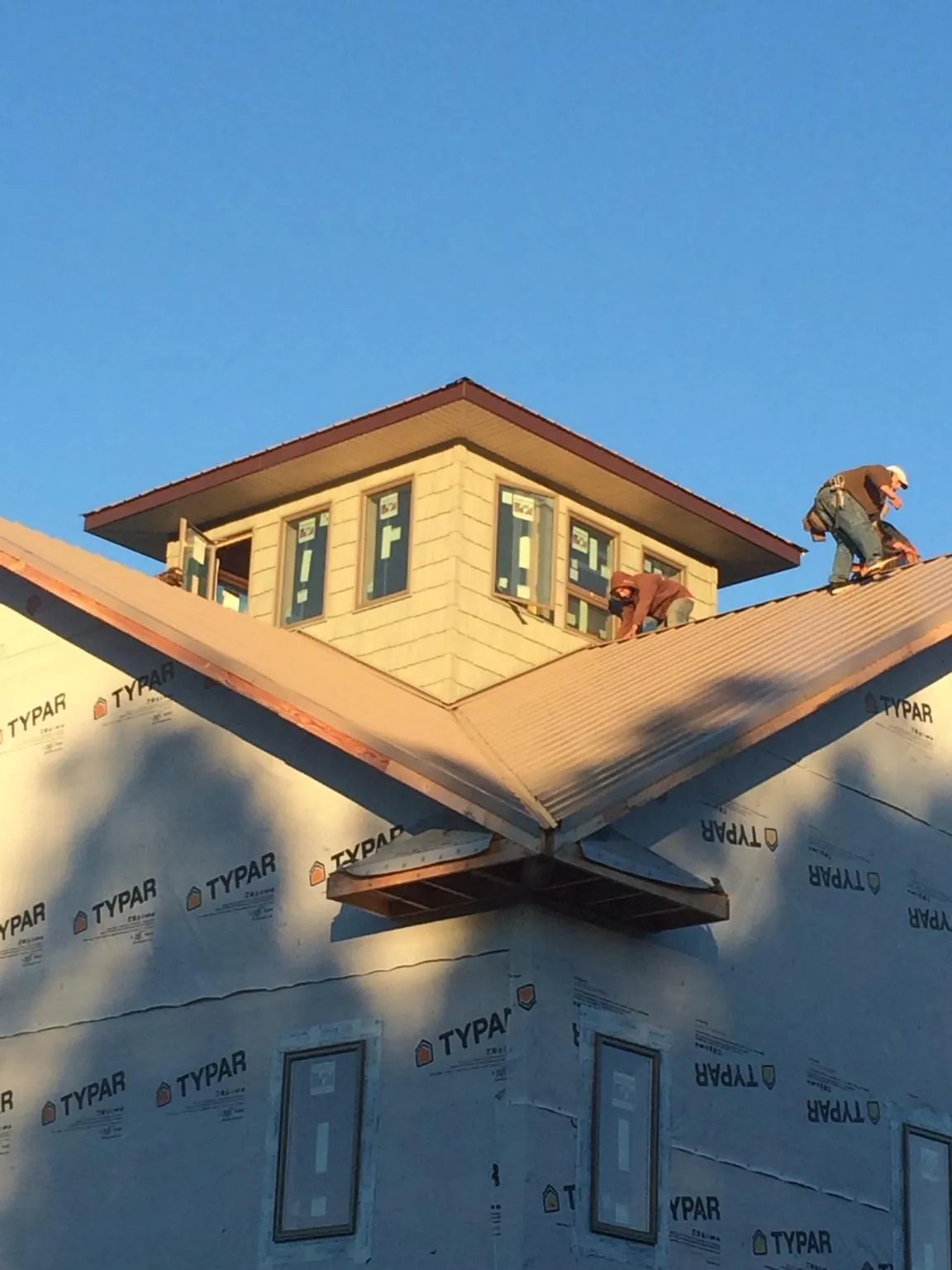 Roofers working around a rooftop cupola on a new metal roof at sunset — Roof Waterproofing in New Baltimore by Roofing Brothers